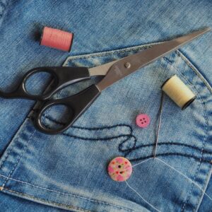 Colorful sewing supplies arranged on blue denim fabric. Ideal for crafting themes.