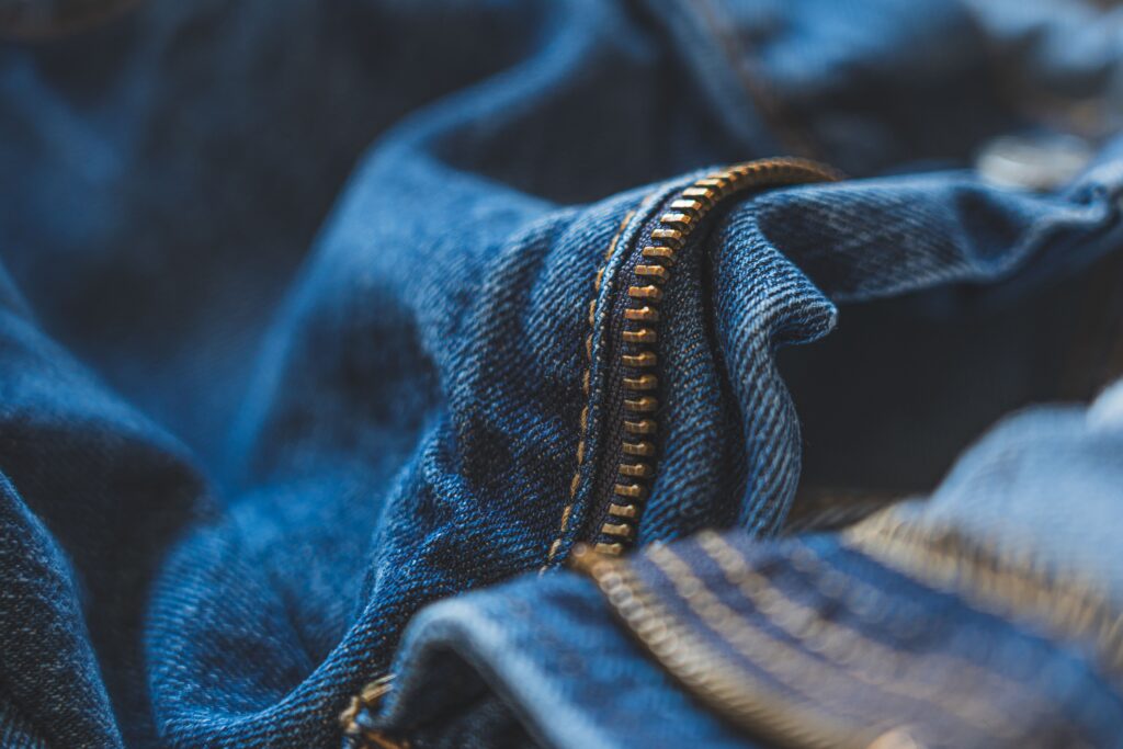 Detailed shot of blue denim fabric and zipper, highlighting texture and fashion element.