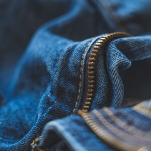 Detailed shot of blue denim fabric and zipper, highlighting texture and fashion element.